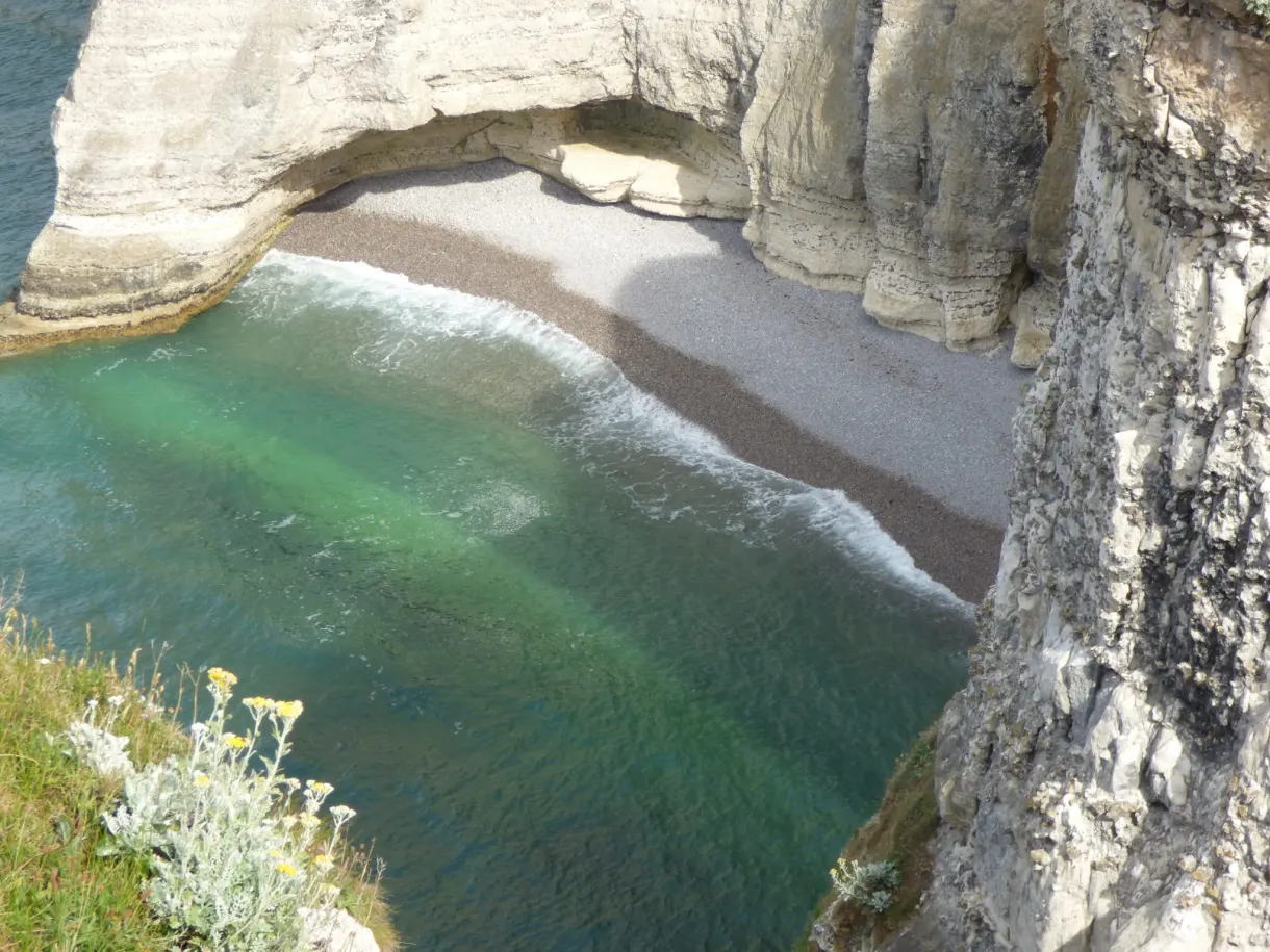 Cove with green waters and pebble beach beneath the arch