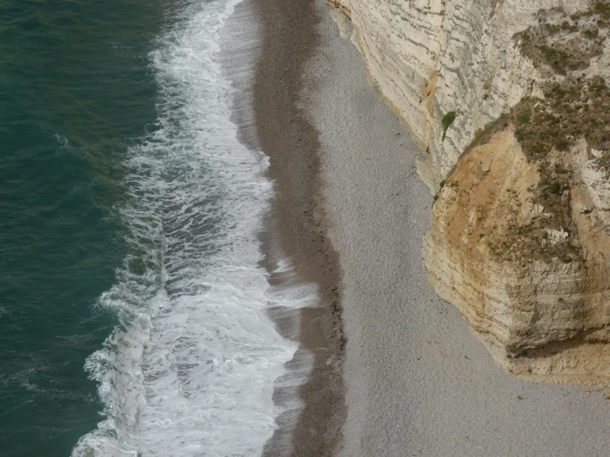 White waves breaking on the ribbon of pebbles at the foot of the cliffs