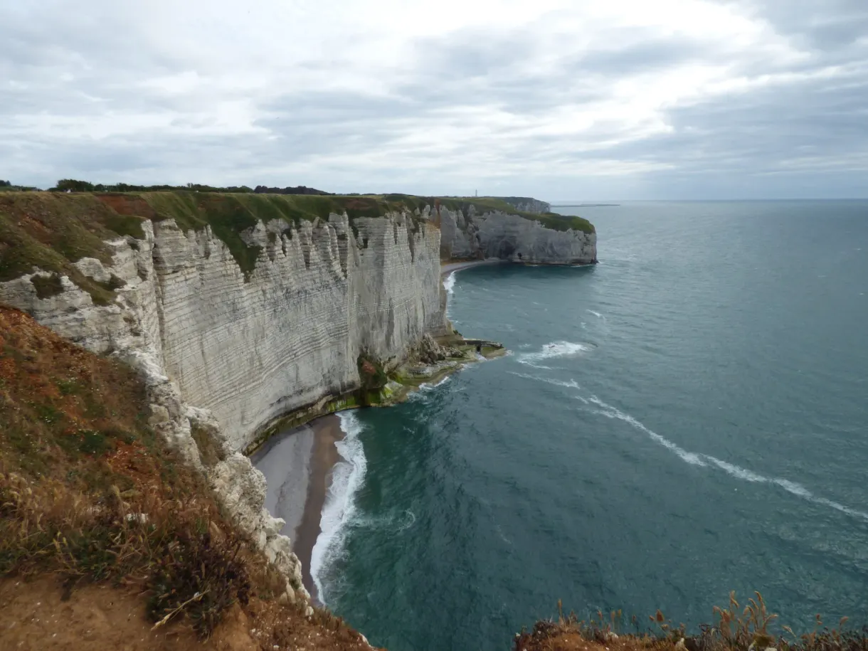Jagged white cliffs and dark inlet under a grey sky