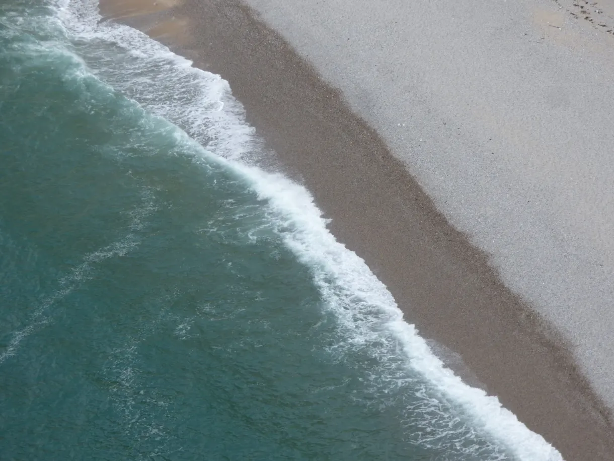Foam from the waves lapping at the bank of pebbles