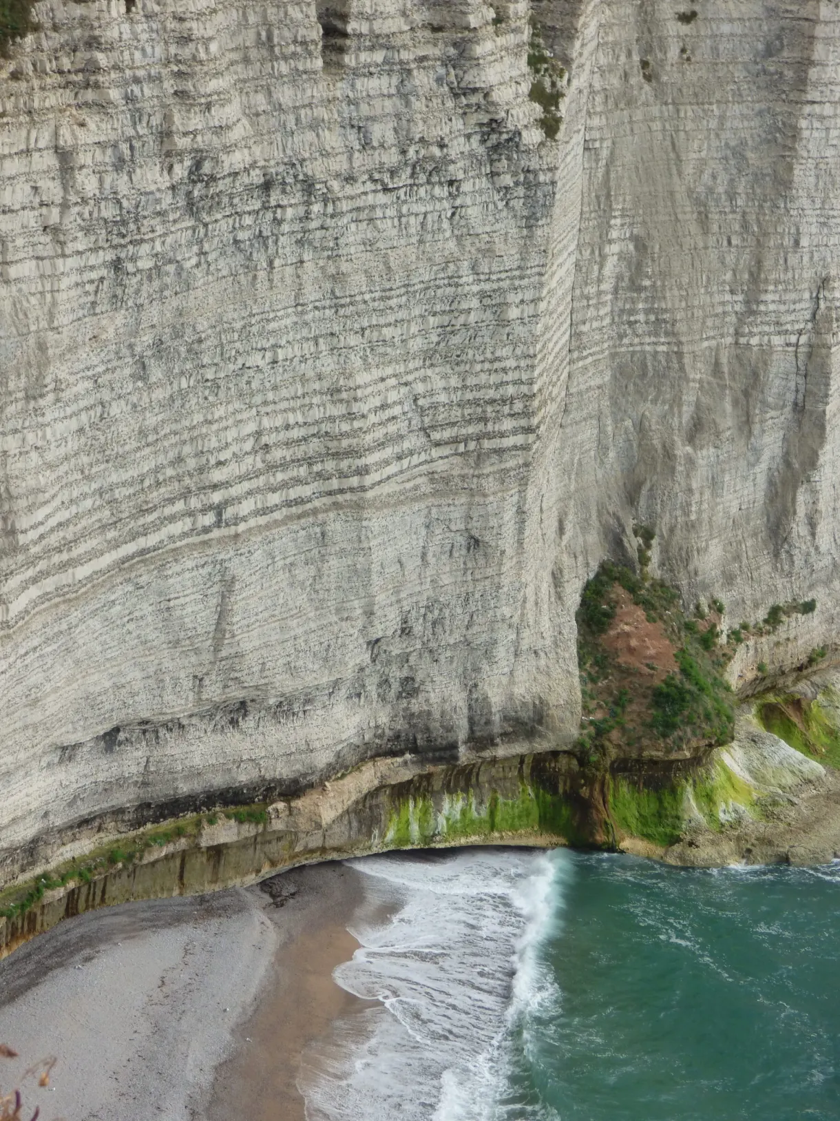 Layered cliff face dropping onto a small beach