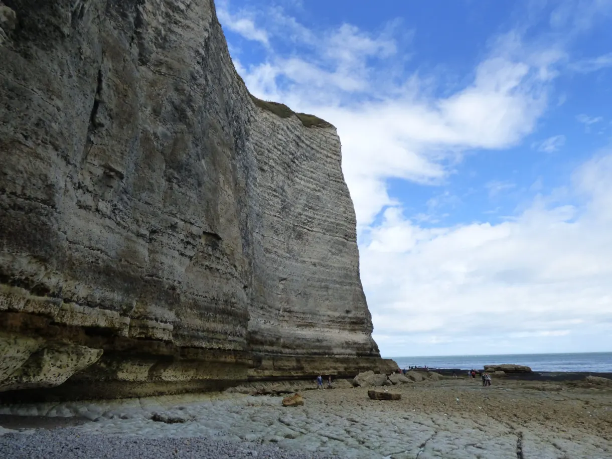 Cliff wall towering over the pebble beach beneath the clouds
