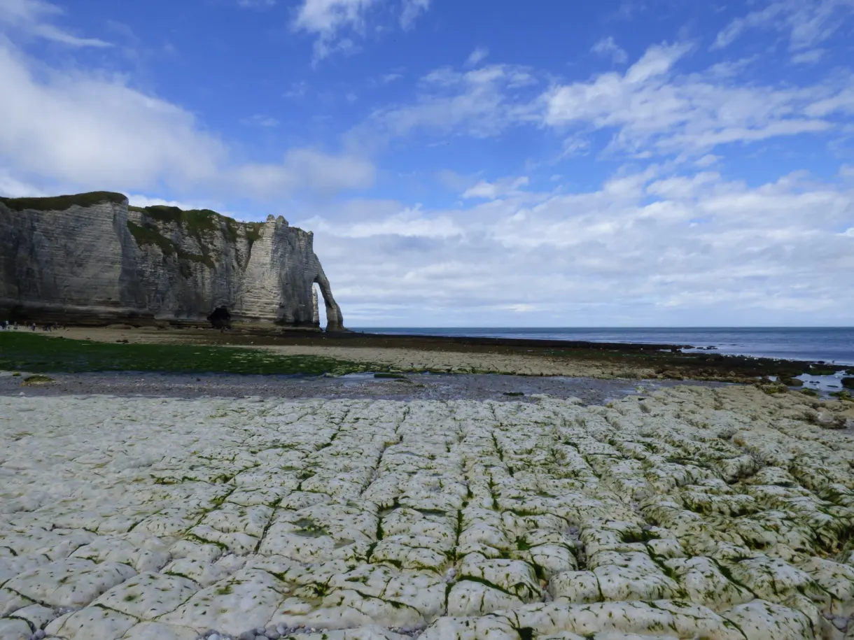 Rock shelf uncovered by the tide in front of the pierced cliff