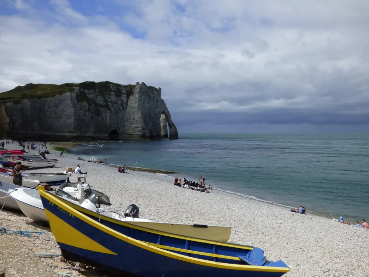 Blue and yellow boat on the pebbles facing the arch