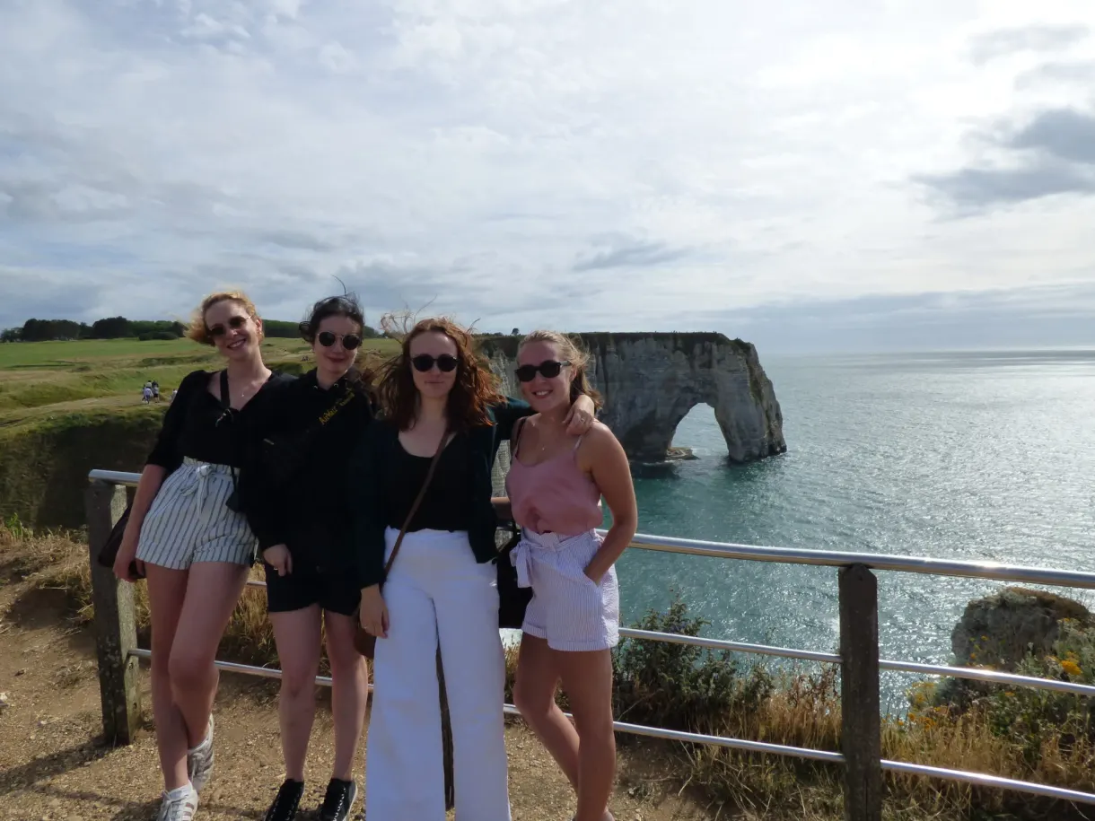 Four friends posing at the railing of the Étretat viewpoint