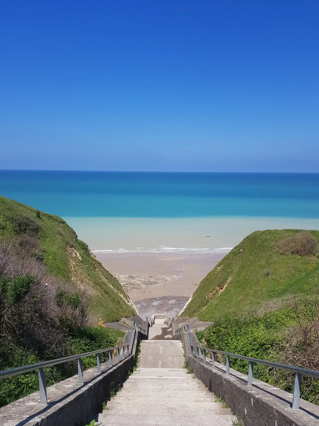 Staircase descending to the beach between two grassy slopes