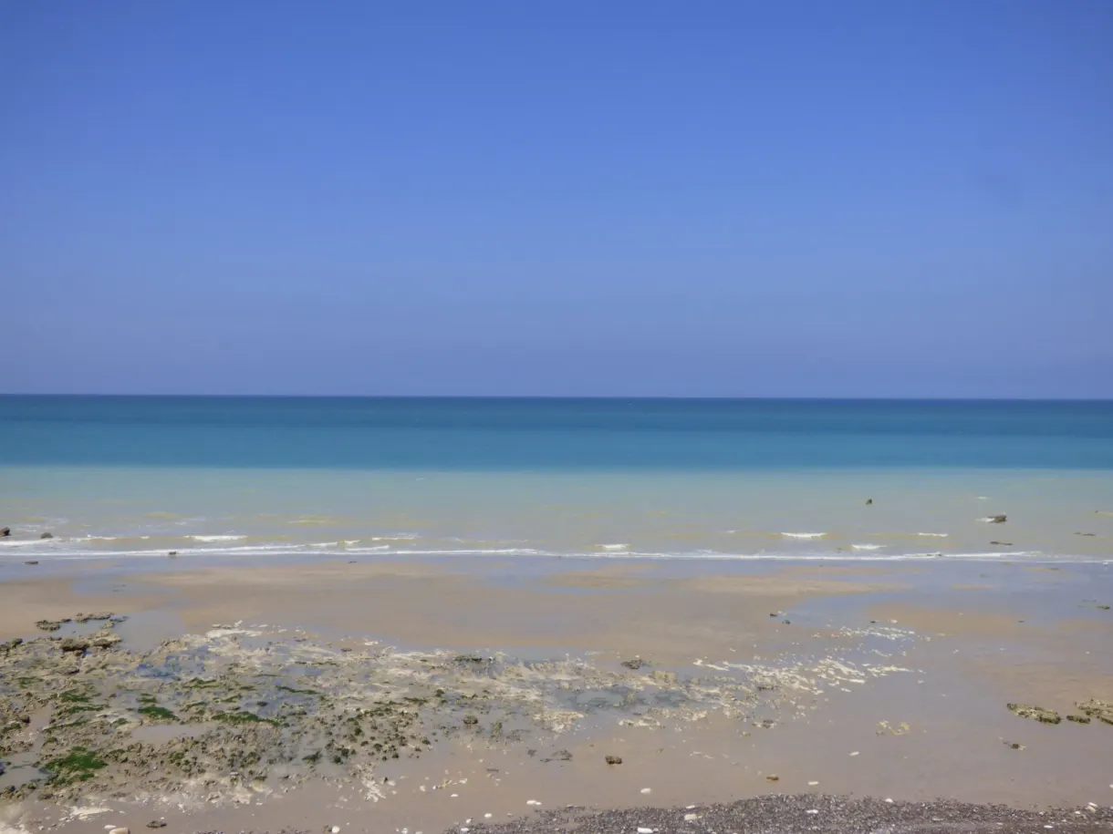 Pale sandy foreshore and calm sea under a blue sky