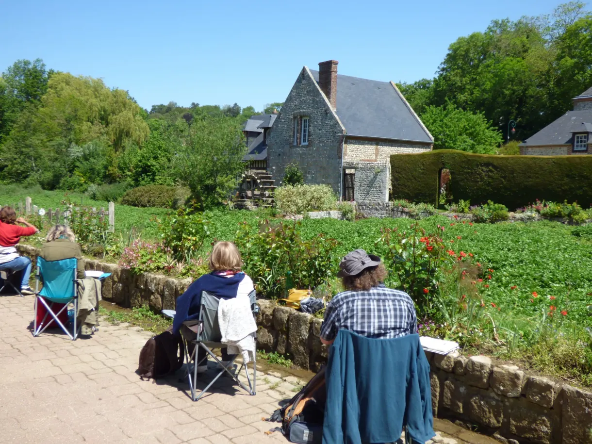 Walkers settled beside a water garden in front of a stone house