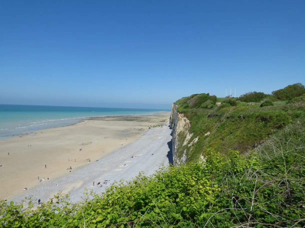 Wide sandy beach seen from the top of the green cliff
