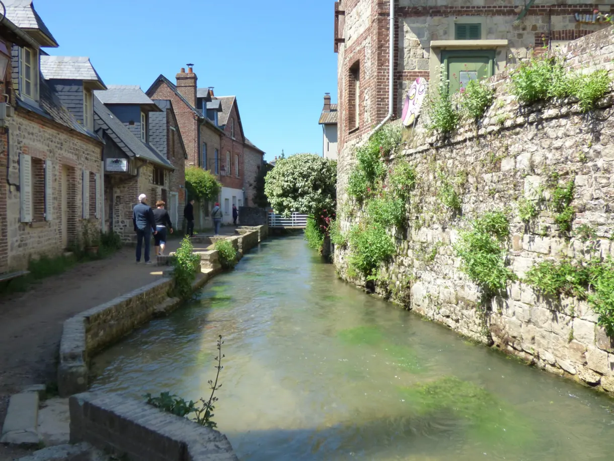 Stream channelled between low stone walls and old houses