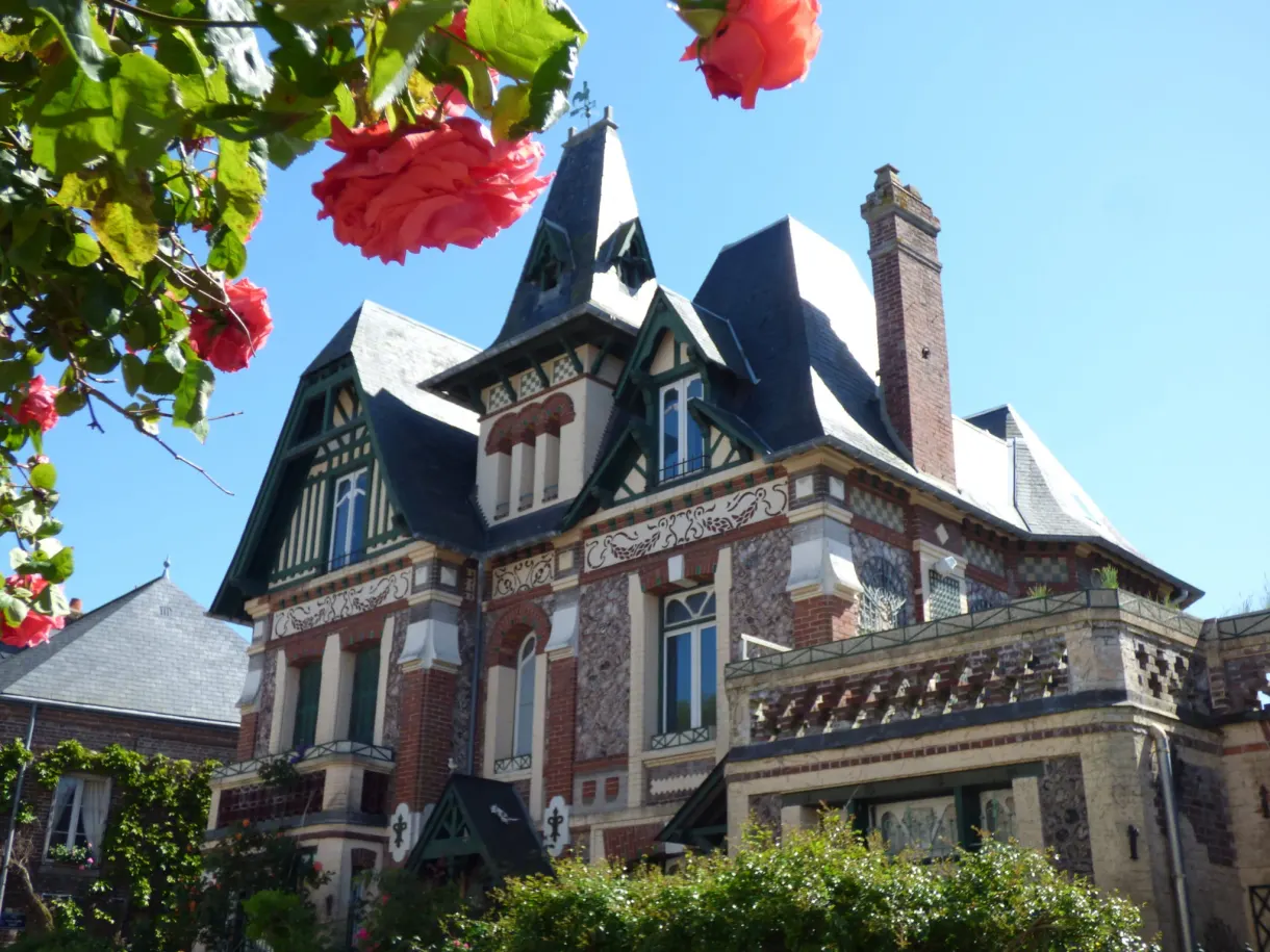 Seaside villa with turrets behind a red rose in bloom