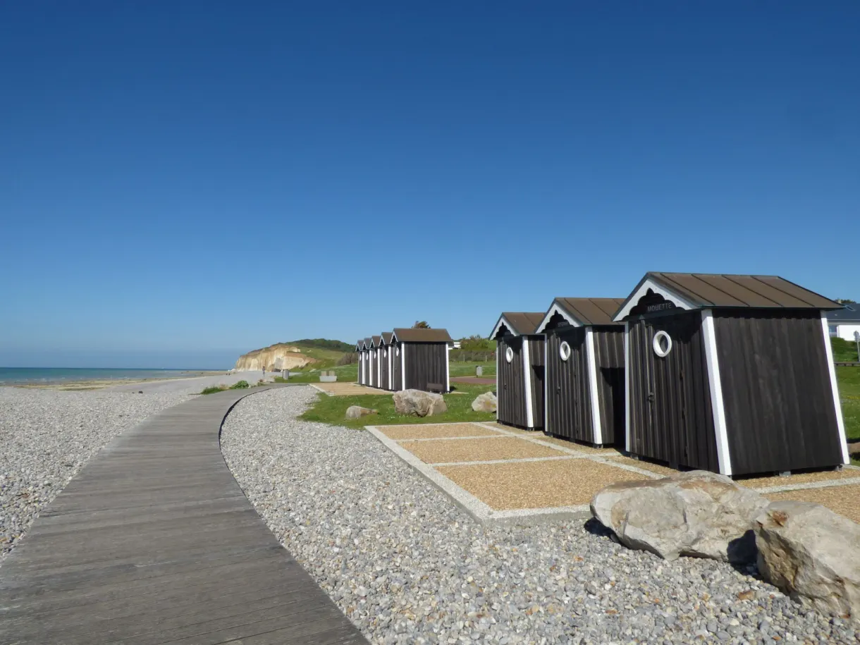 Wooden beach huts lined up along the path, at the end of the day