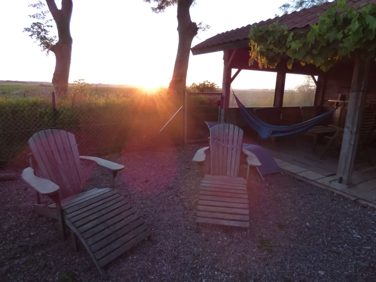 Garden armchairs and pergola facing the setting sun