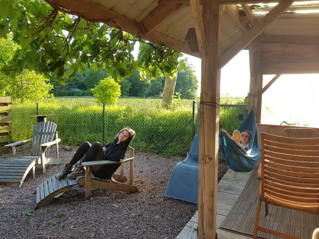 Woman lying under the wooden pergola near a hammock