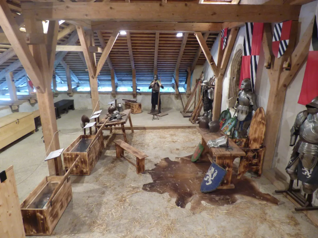 Wooden vaulted hall filled with armour and banquet tables