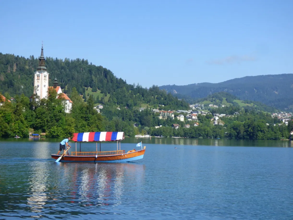 Boat with a striped awning in front of the island and its bell tower