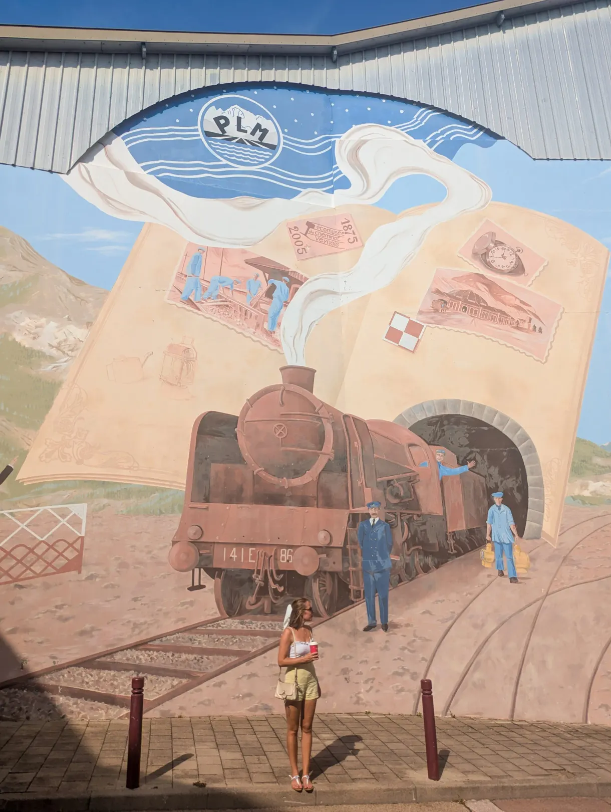 Wall fresco of a steam locomotive with a visitor posing in front of it
