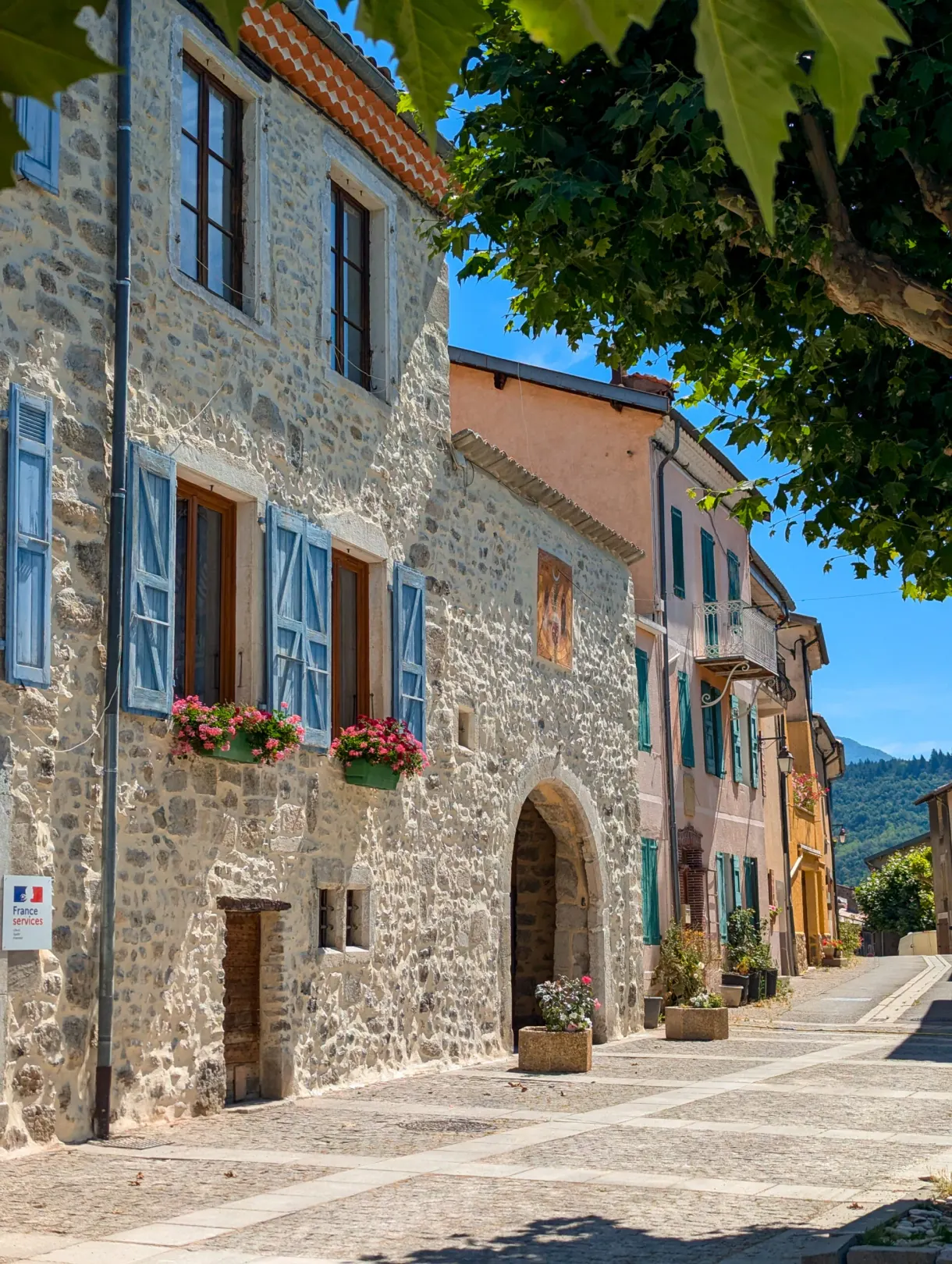 Cobbled street lined with stone houses with blue shutters