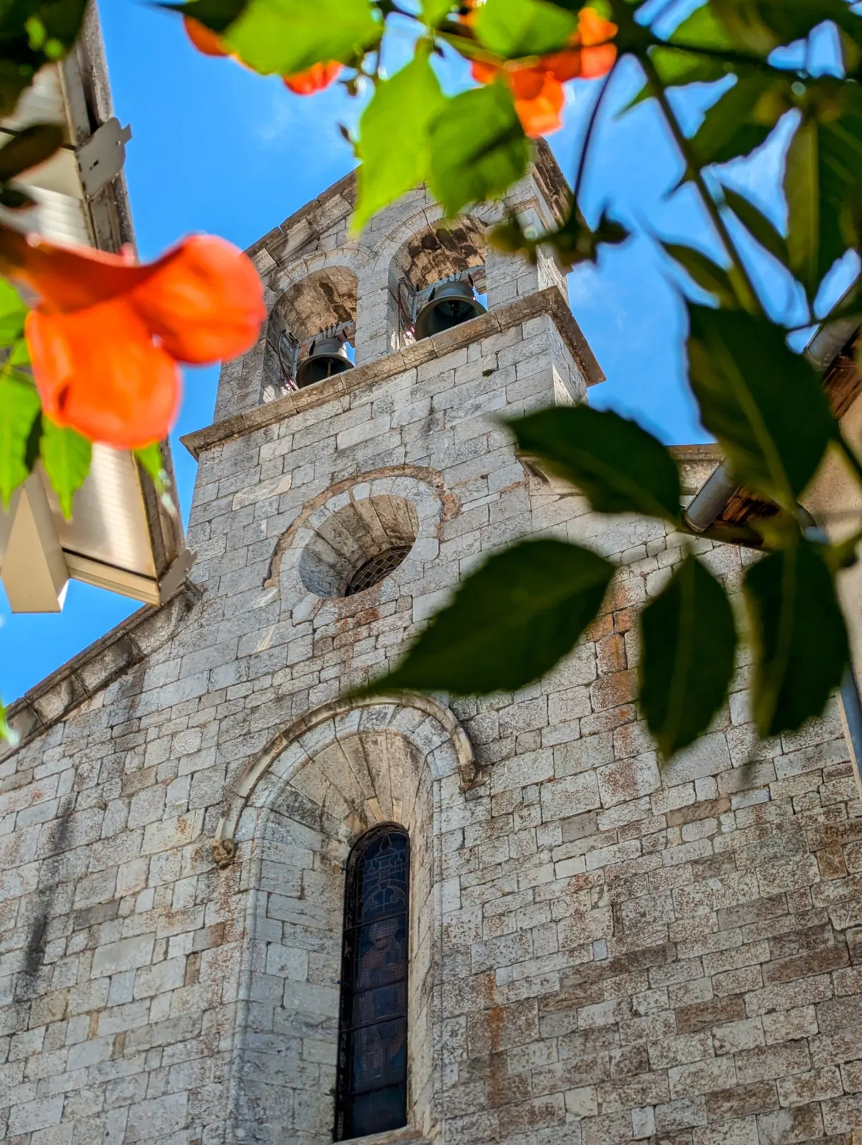 Stone bell tower glimpsed between the foliage and orange flowers