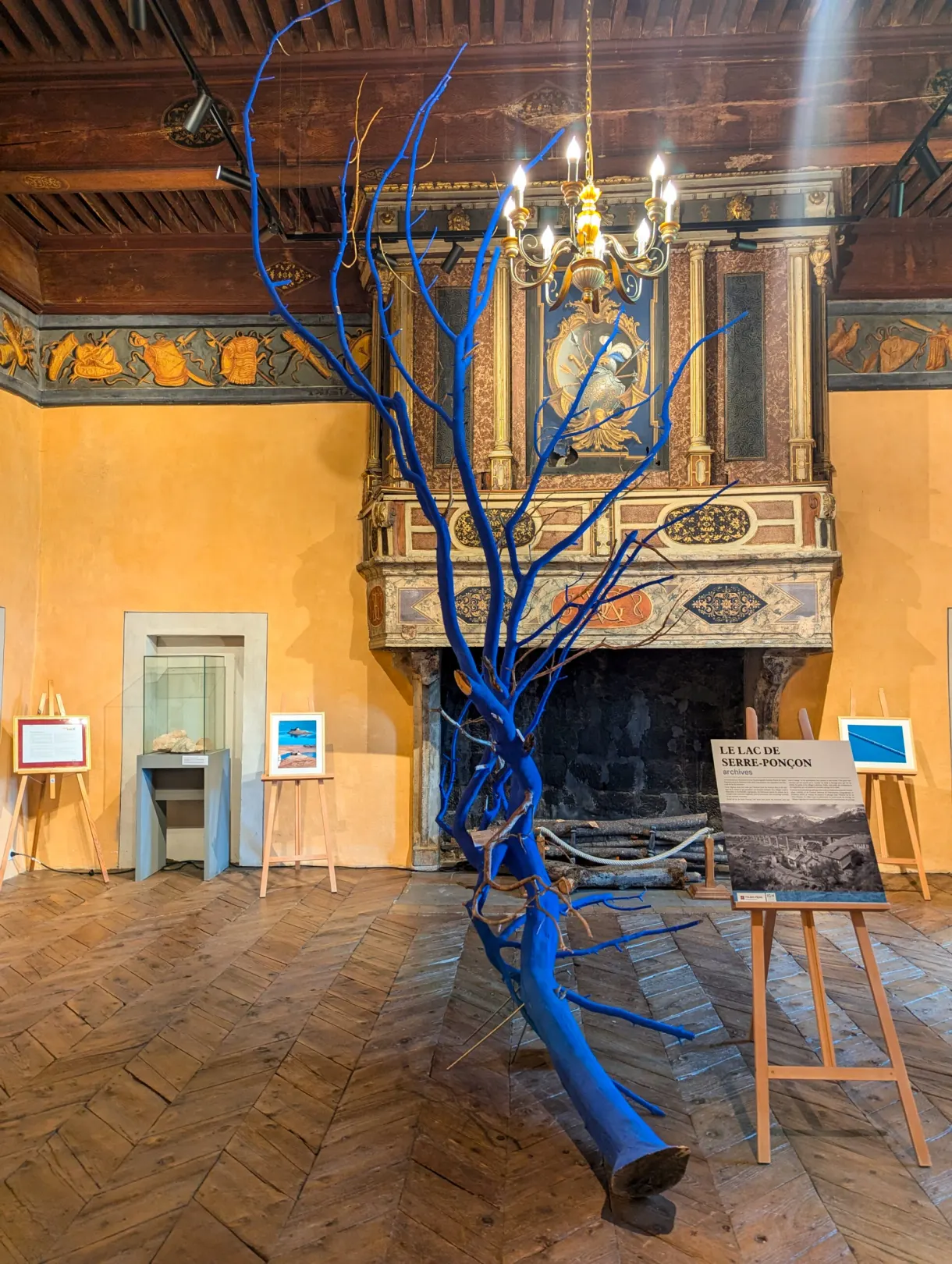 Blue tree sculpture set in front of the fireplace of a painted room
