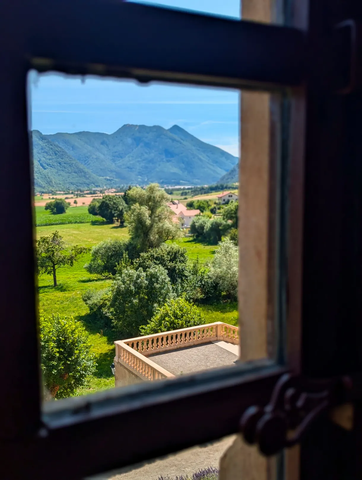 Open window framing the meadows and the mountain