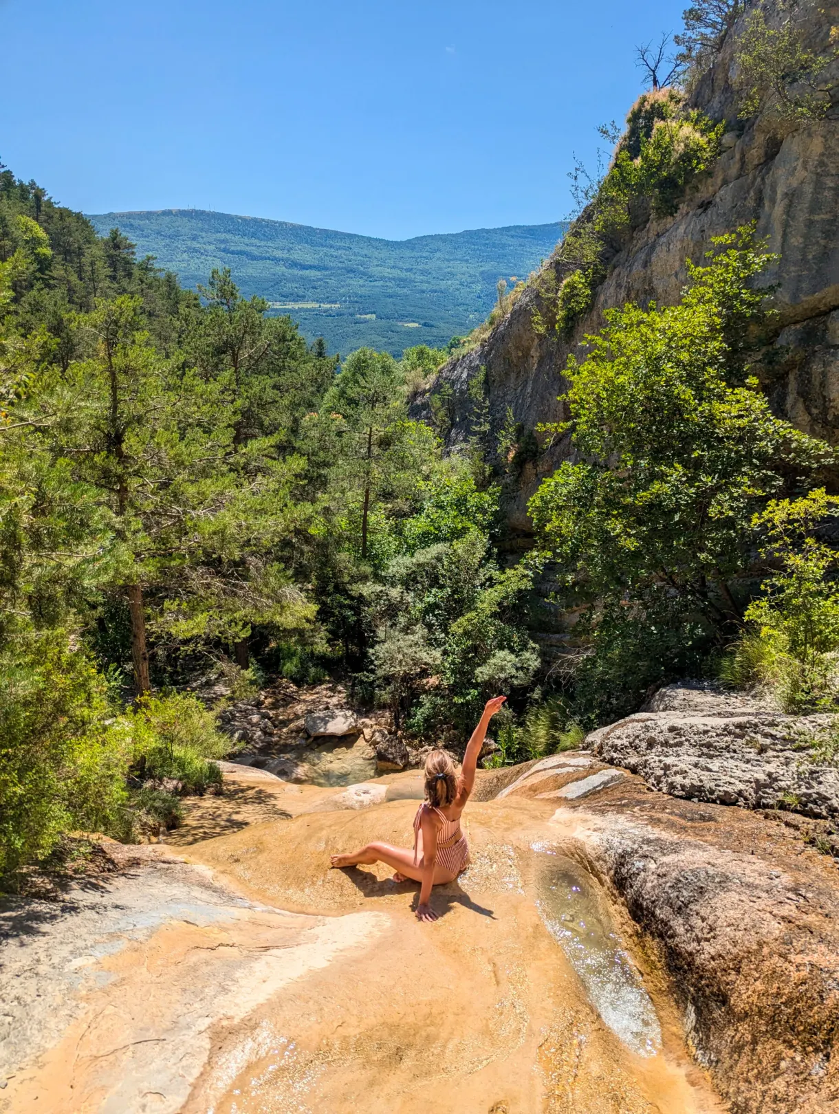 Bather with arms raised in the middle of the slabs of the torrent