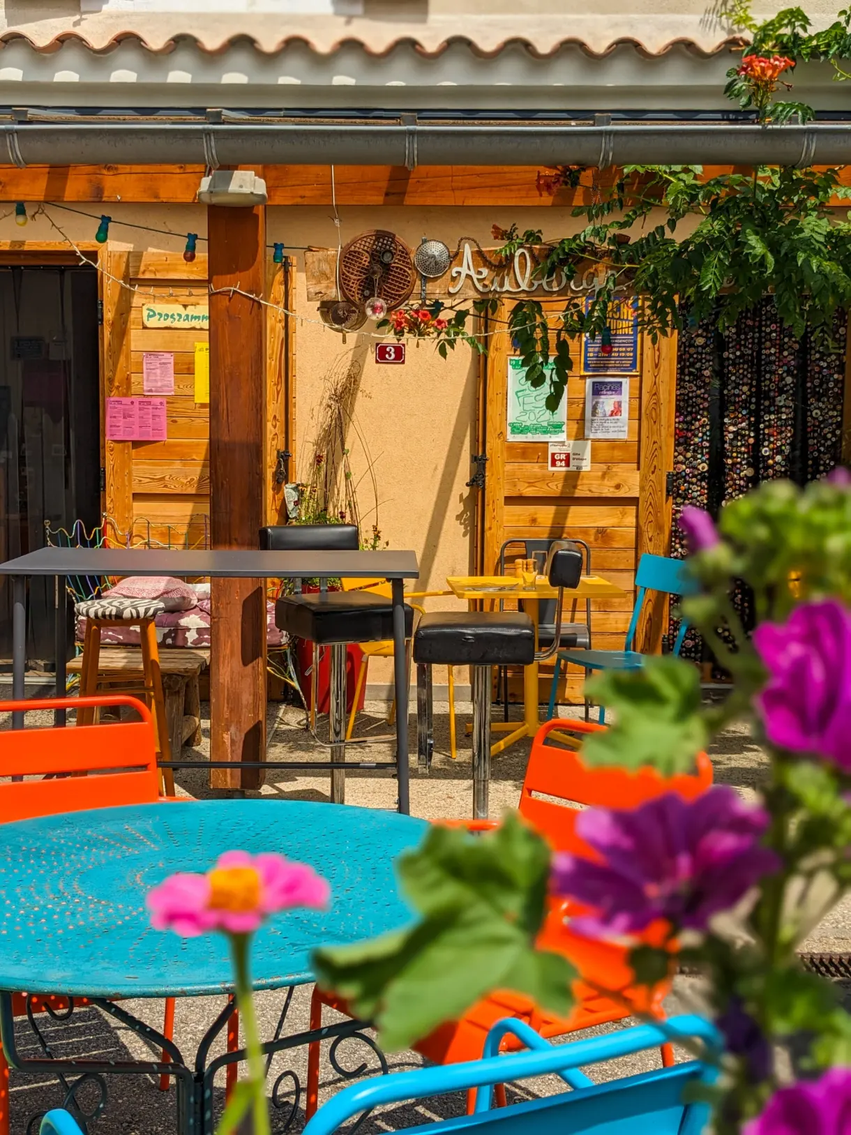 Terrace with turquoise tables and potted flowers in front of the restaurant