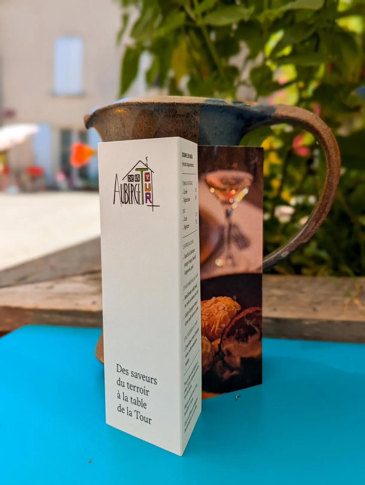 Restaurant menu resting on a turquoise table beside a jug