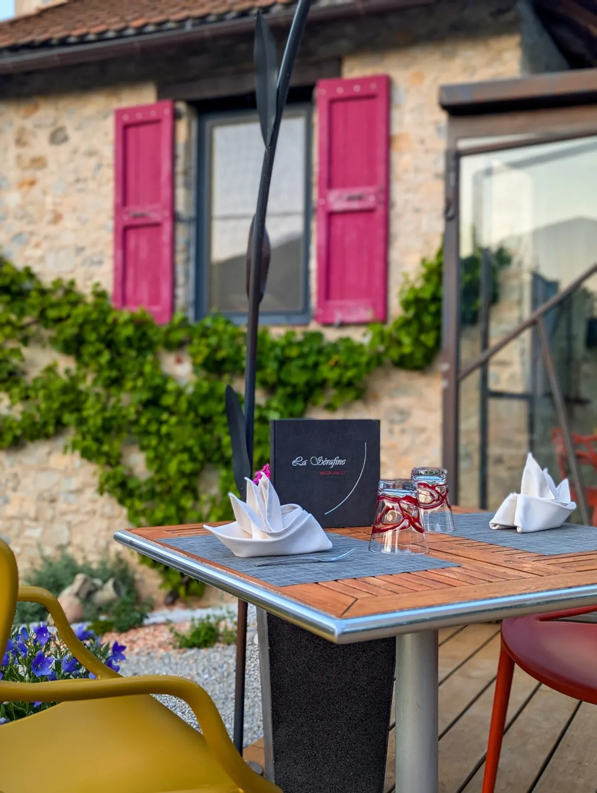 Table laid on the terrace in front of a facade with pink shutters