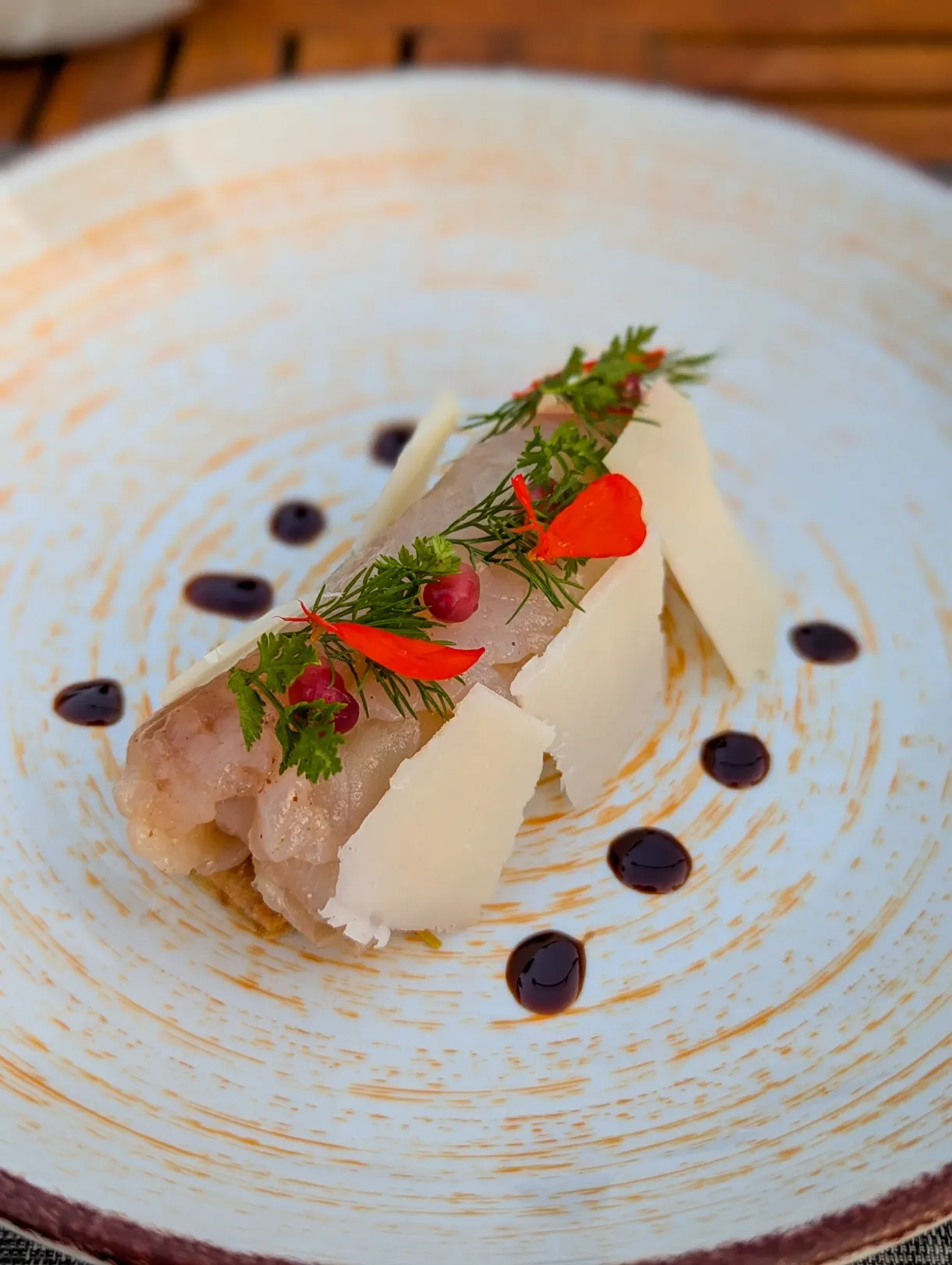 Carpaccio topped with shavings of cheese and edible flowers