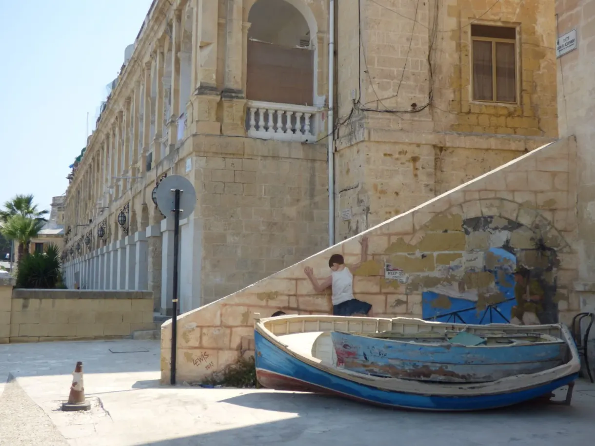 Old blue boat set on land in front of a stone palace
