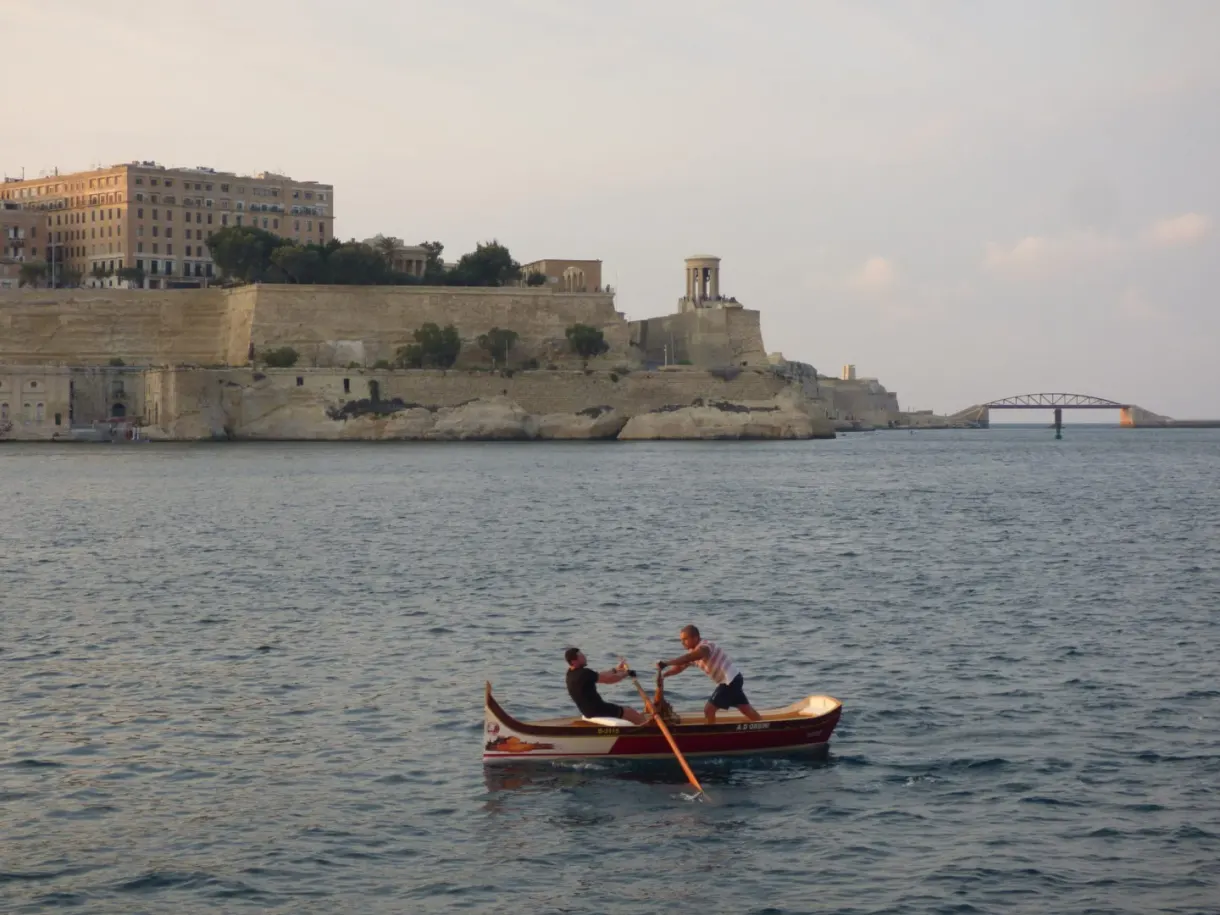 Two rowers in a boat in front of the fortifications