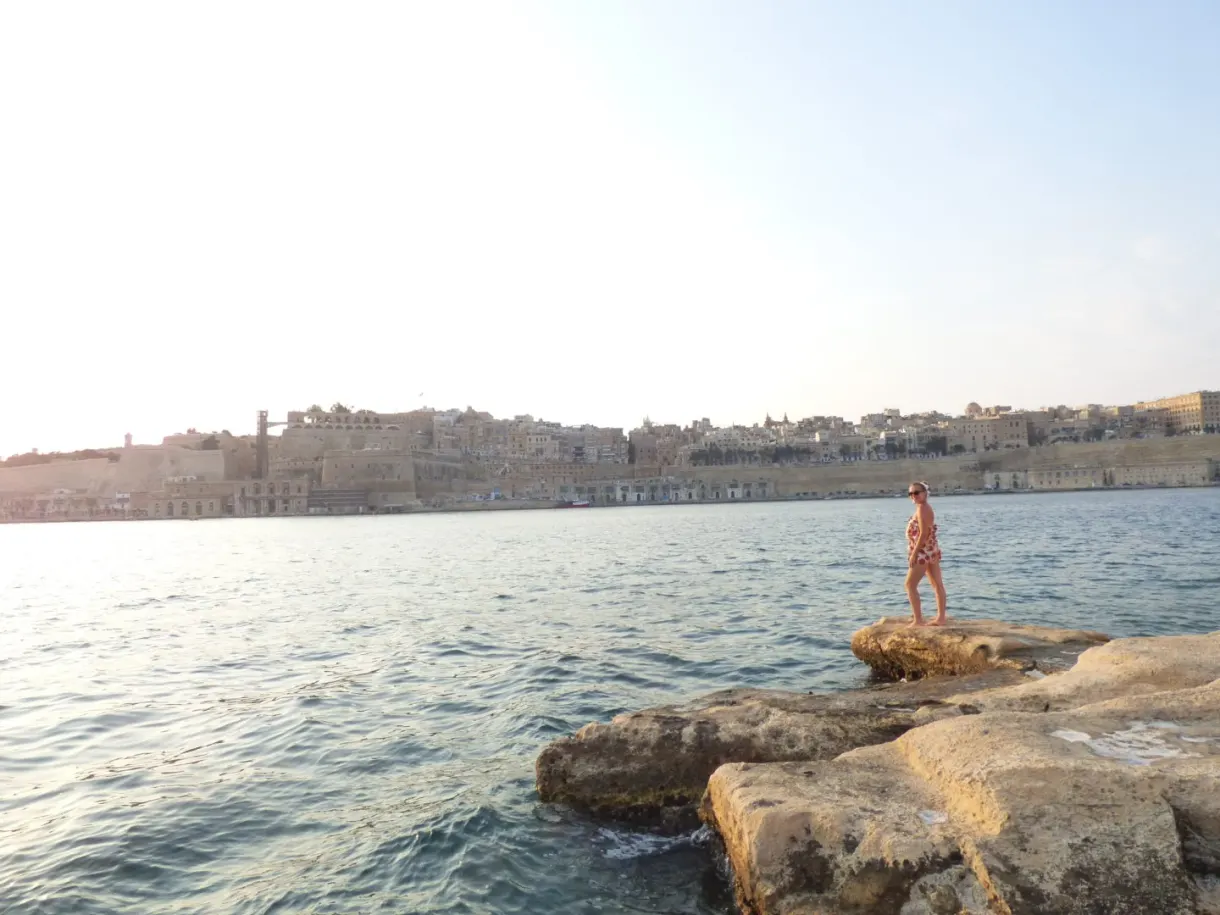 Figure standing on the rocks facing the city
