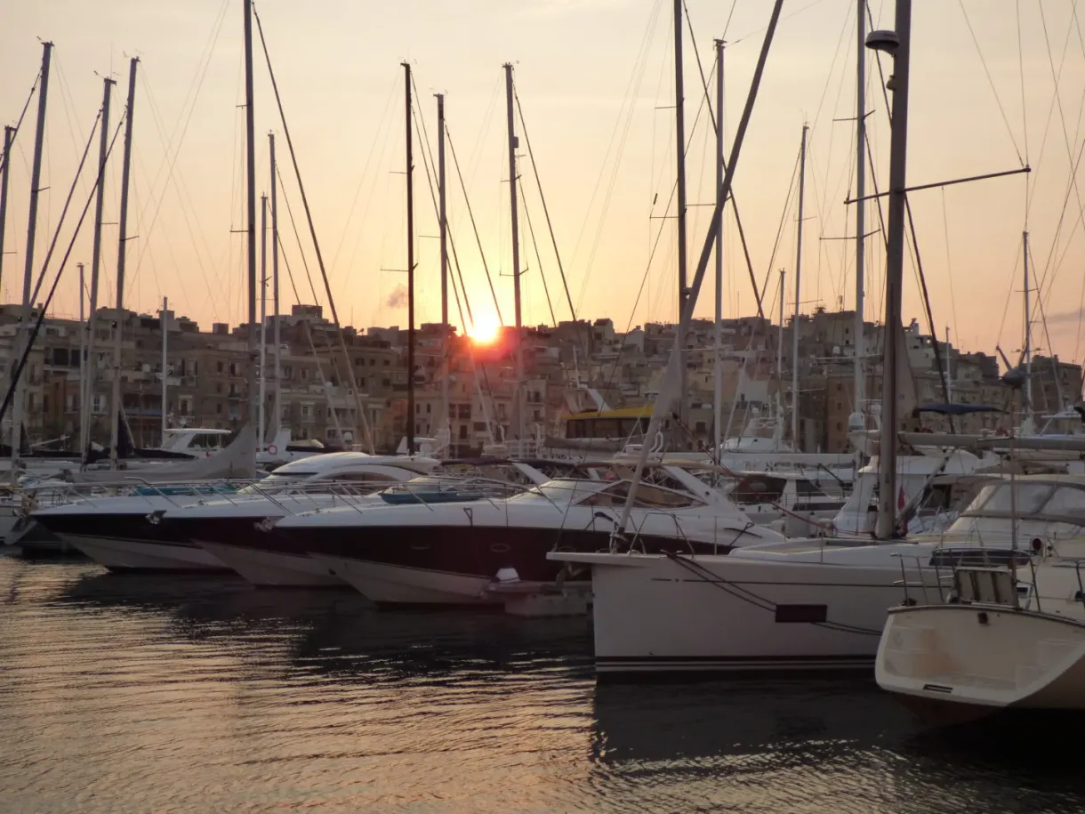 Setting sun filtering between the masts of the sailing boats