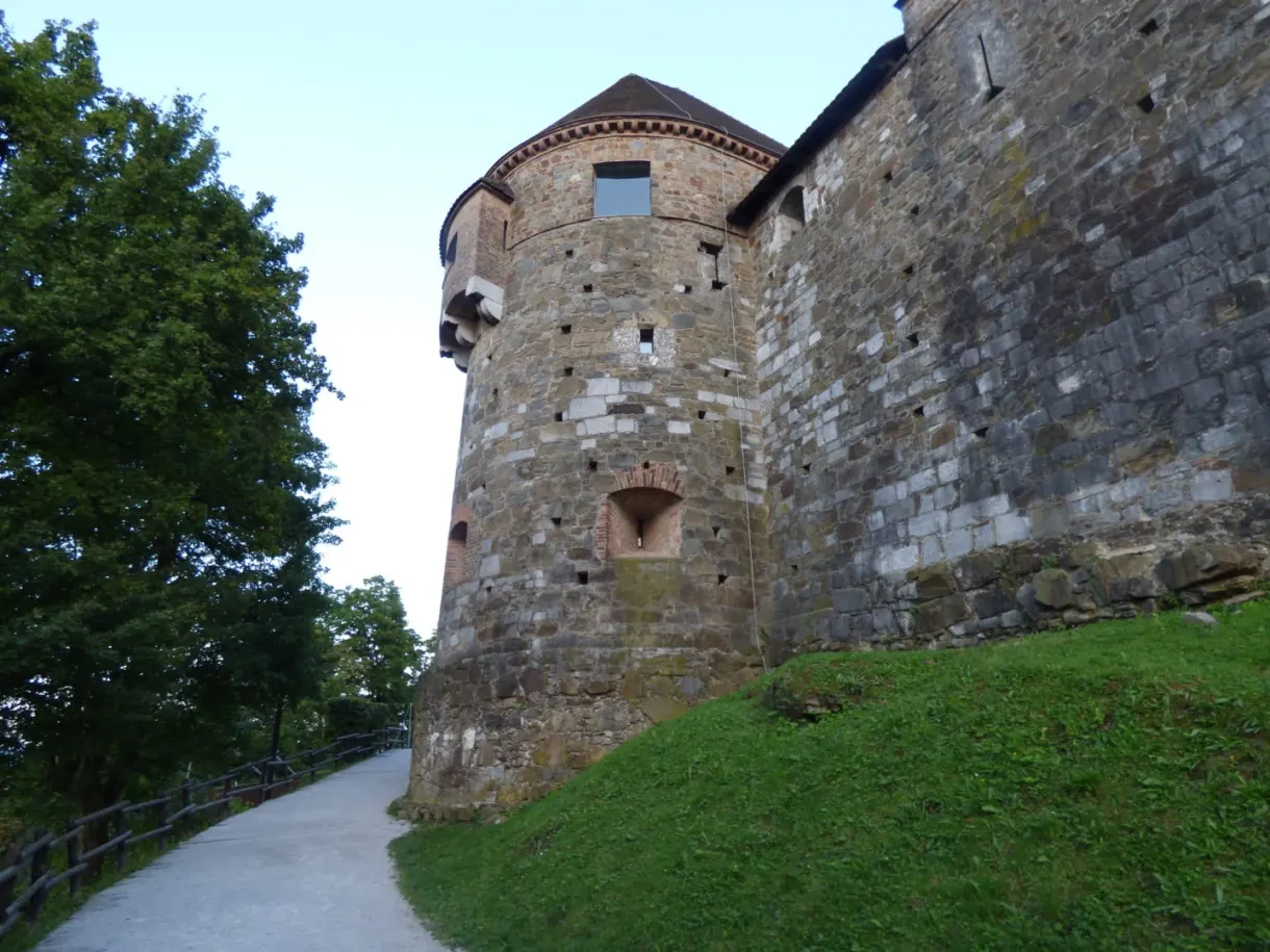 Round stone tower of the castle above a grassy bank