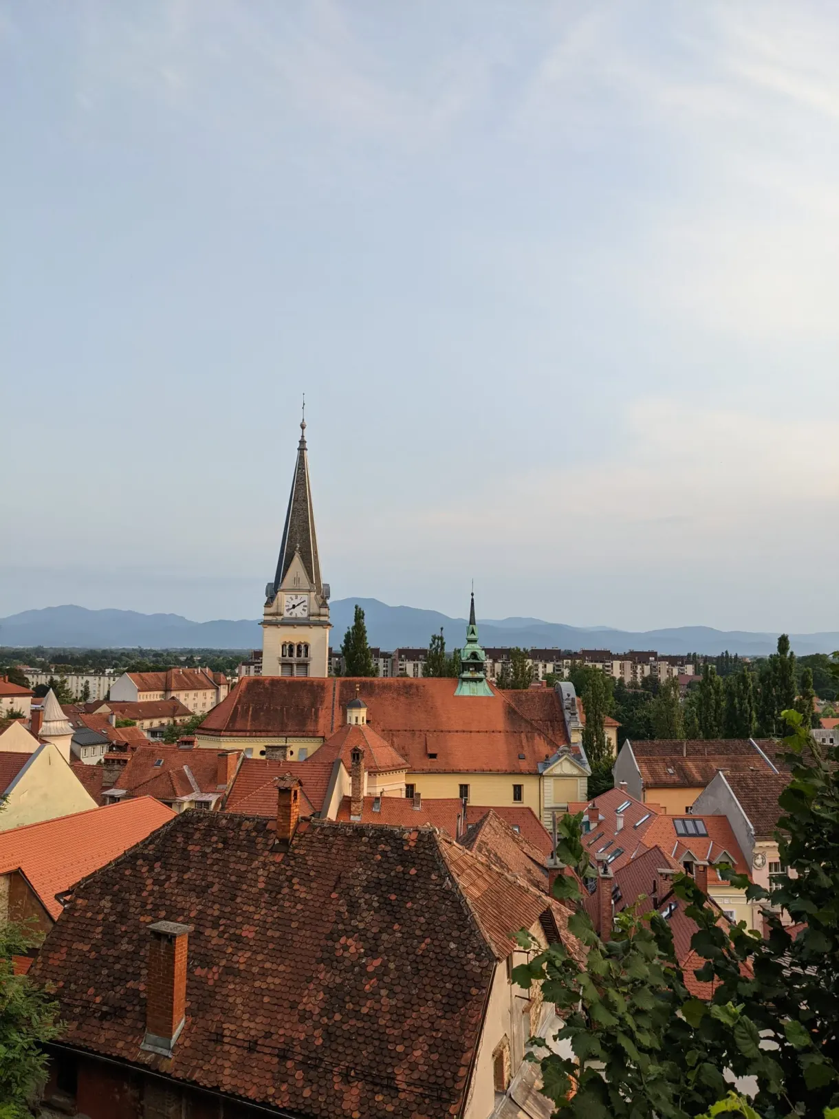 Pointed steeple emerging from the tiled roofs at dusk