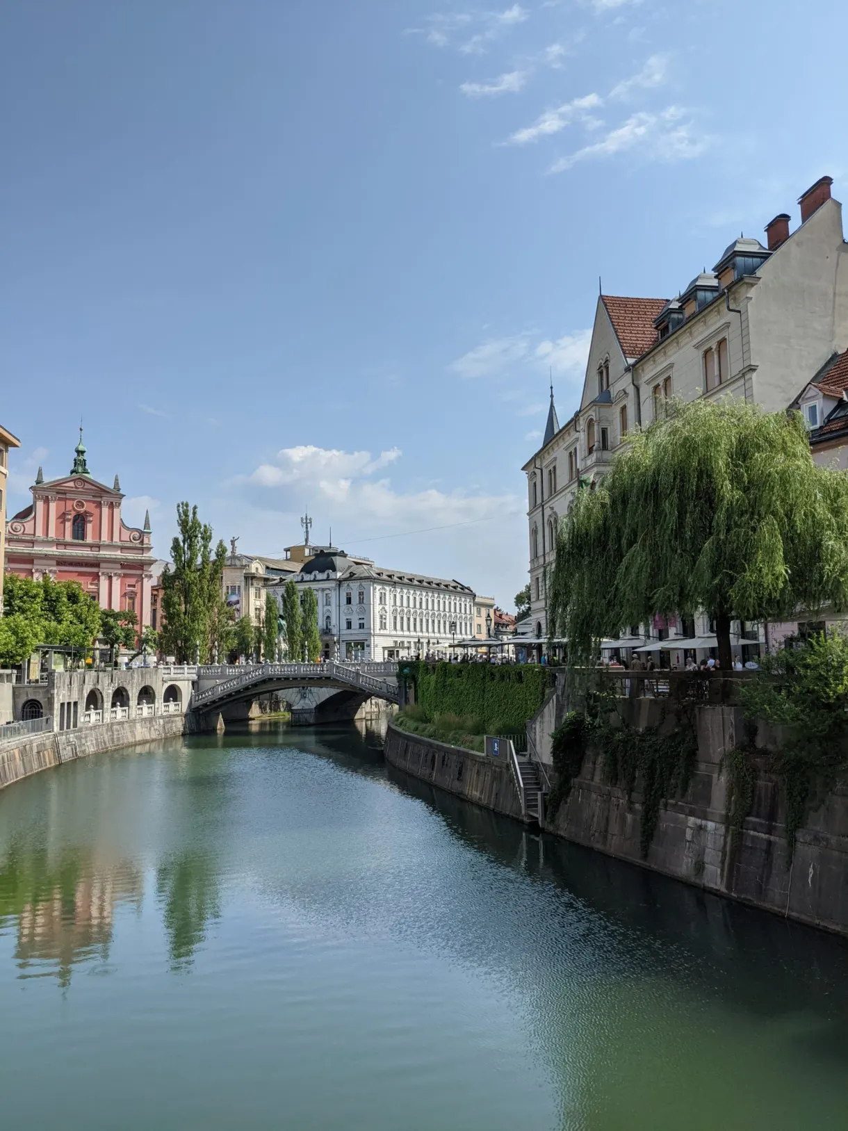 White arched bridge and pink bell tower at the water's edge