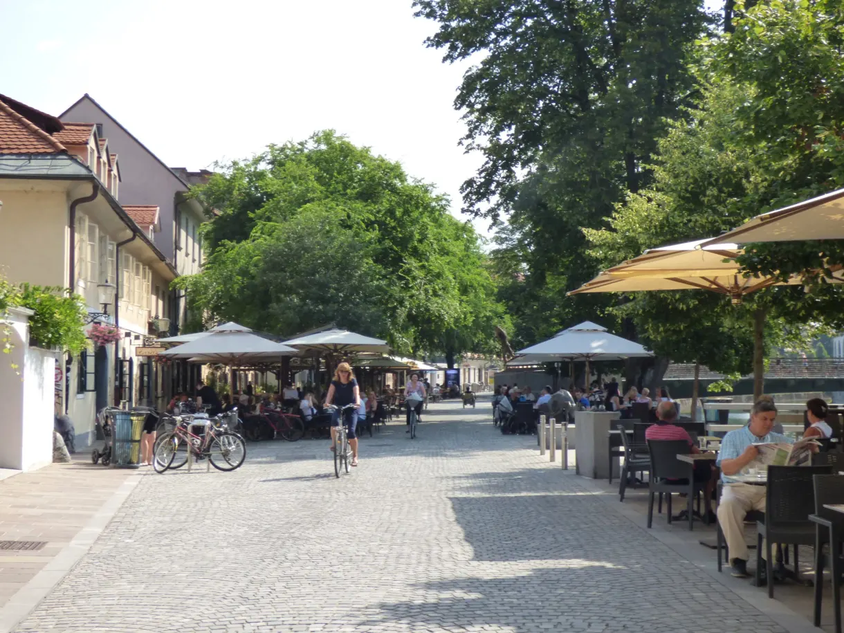 Shaded terraces and cyclists on the pedestrian quay