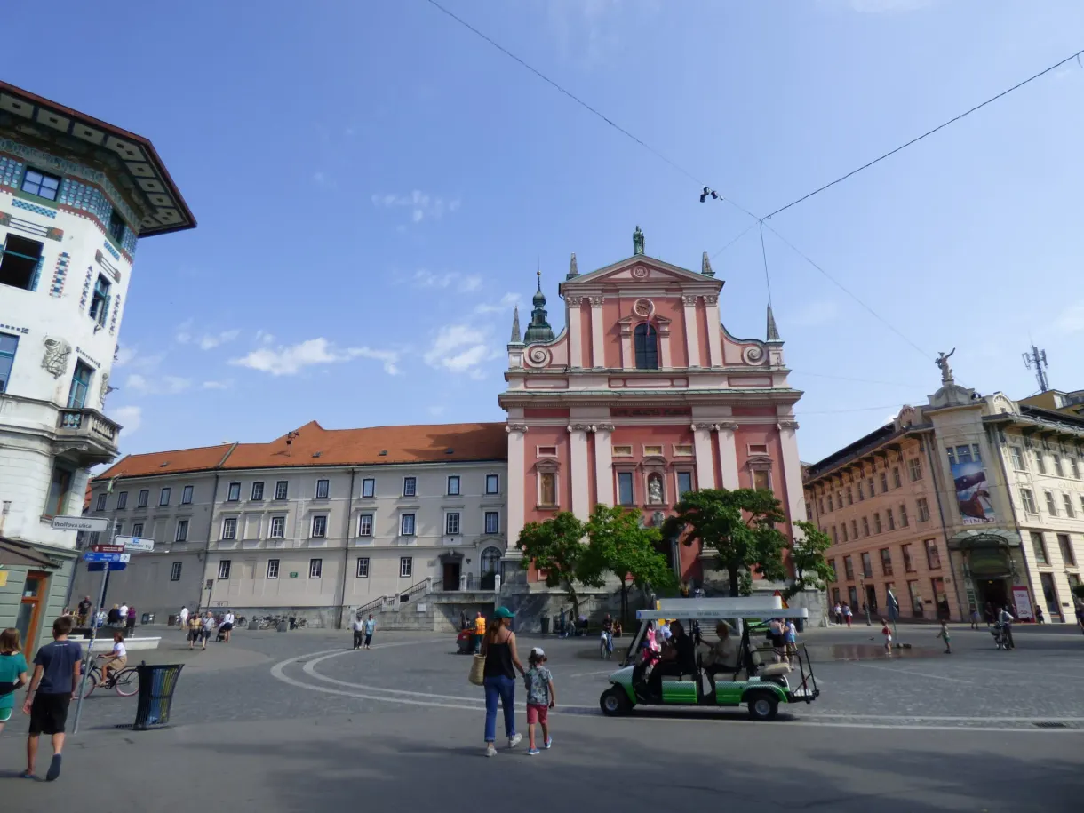 Paved square in front of the pink church, green electric shuttle