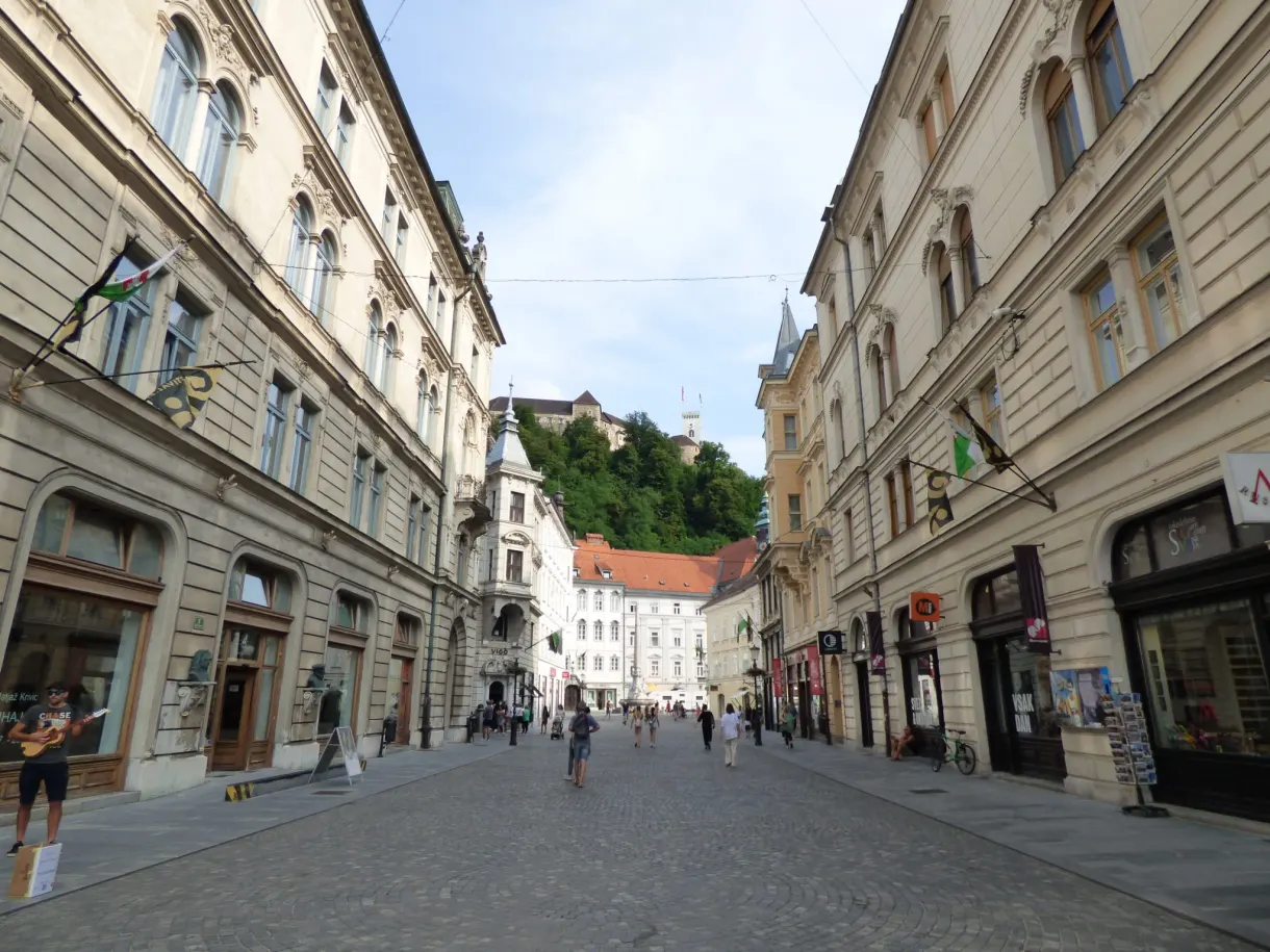 Pedestrian shopping street climbing towards the wooded hill