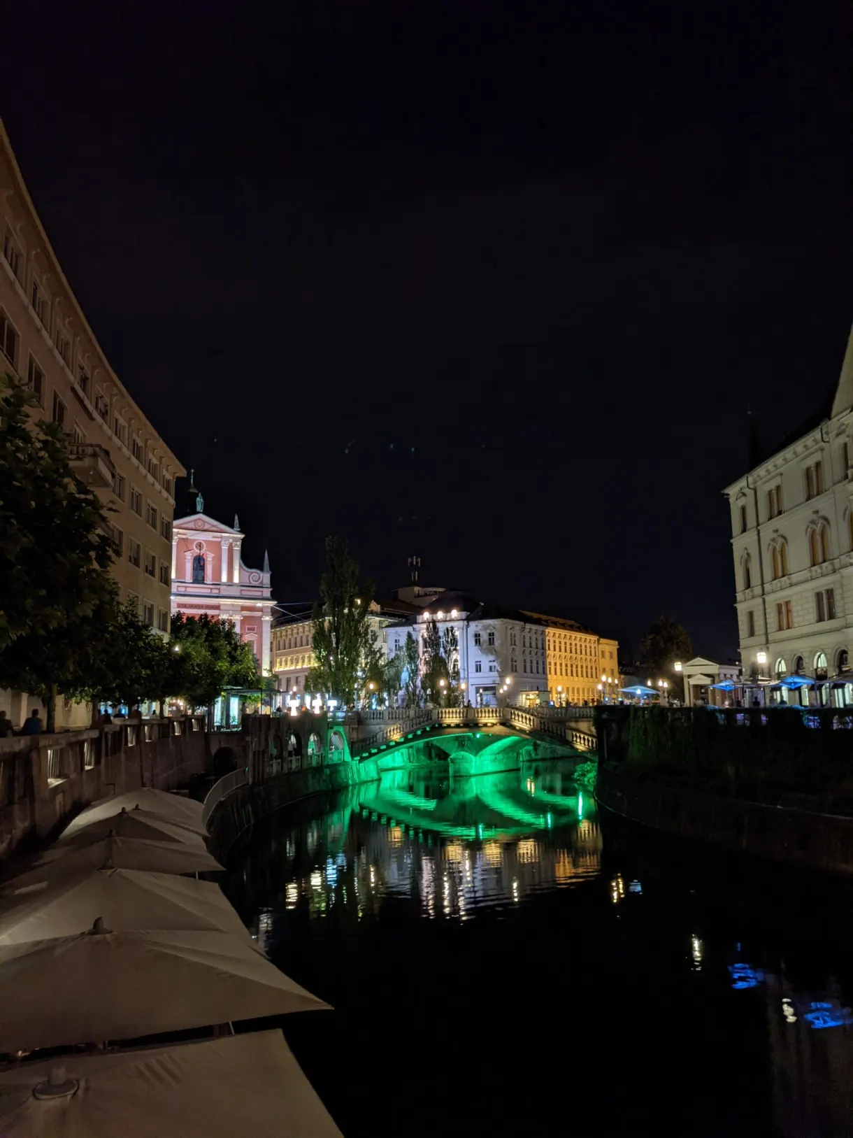 Green light of the bridge reflected on the river at night