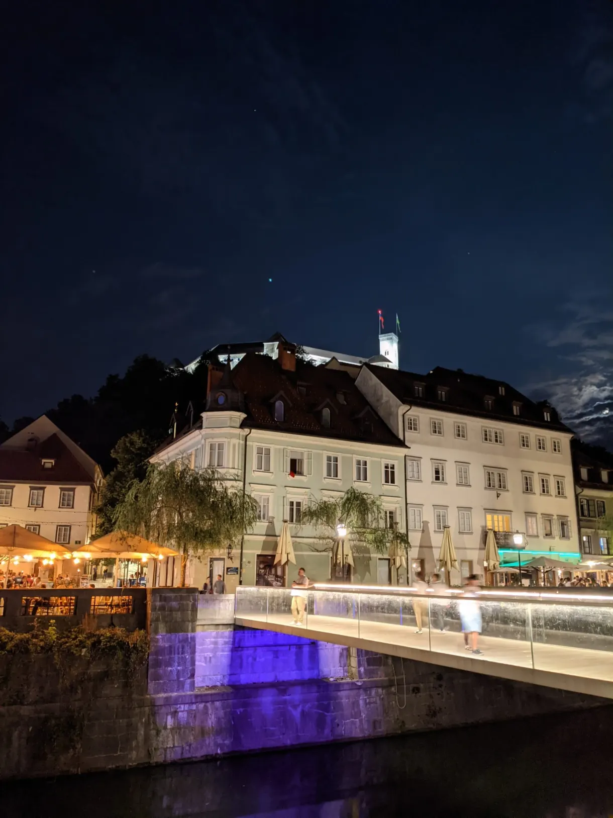 Illuminated castle above the lit terraces of the quay