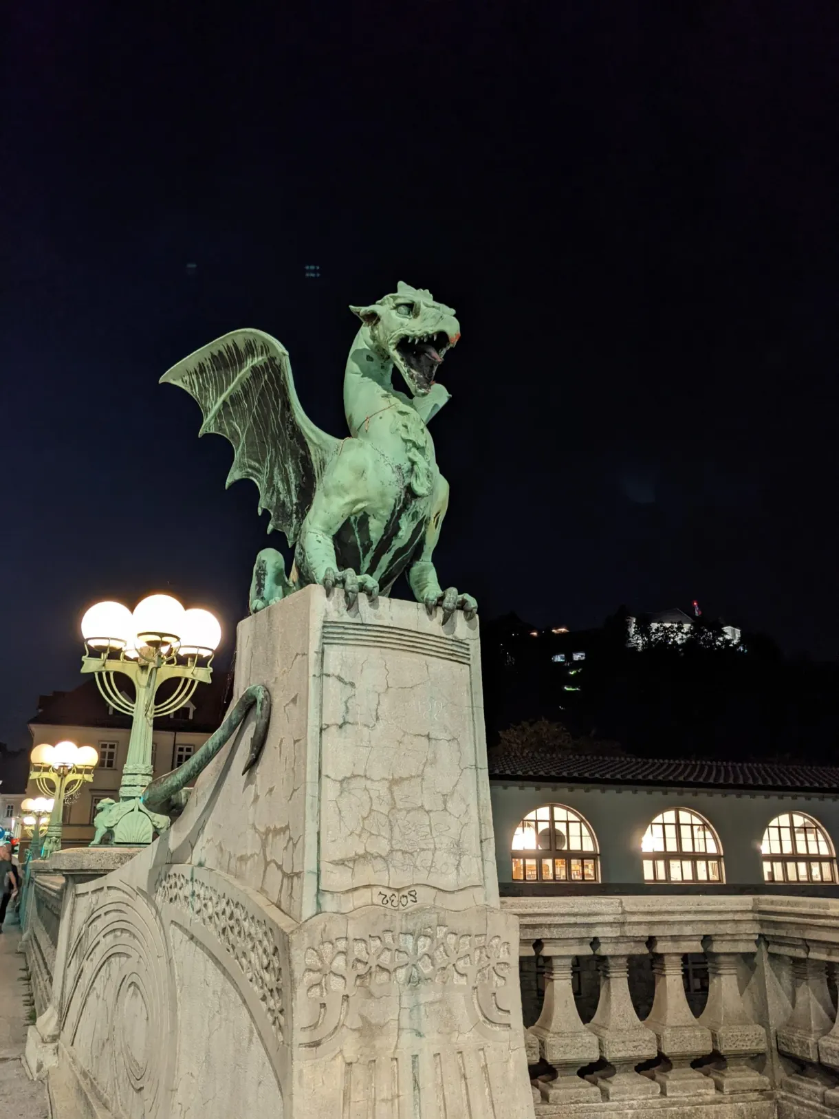 Bronze dragon of the bridge under the lit street lamps