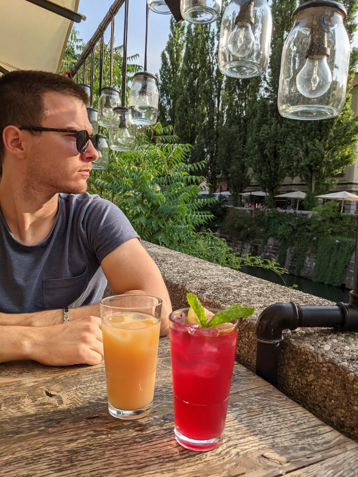 Man leaning on a terrace at the water's edge, two cocktails