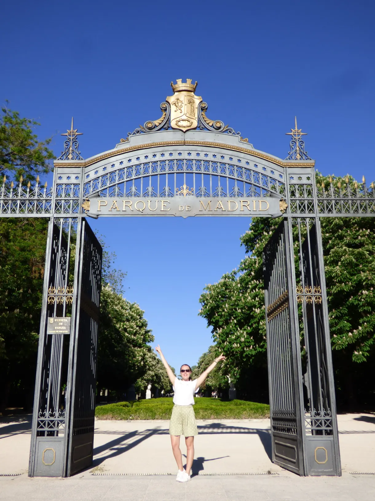 Wrought iron gate of the park, arms raised beneath the arch