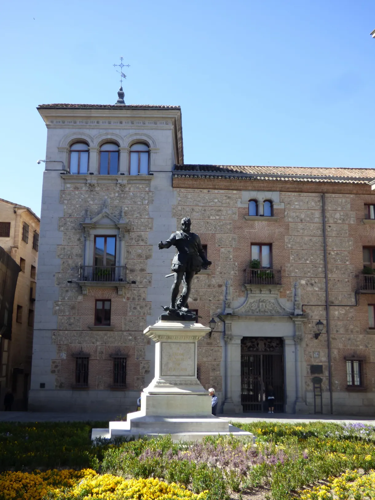 Bronze statue in front of a palace of stone and brick