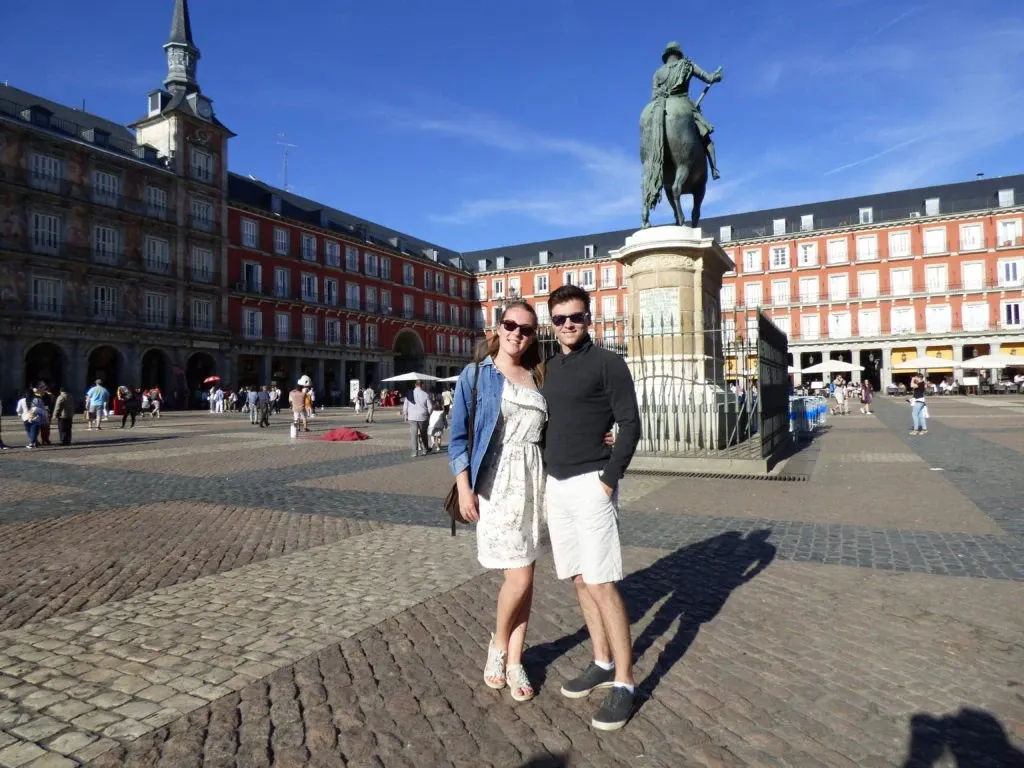 Couple posing in front of the equestrian statue of the Plaza Mayor