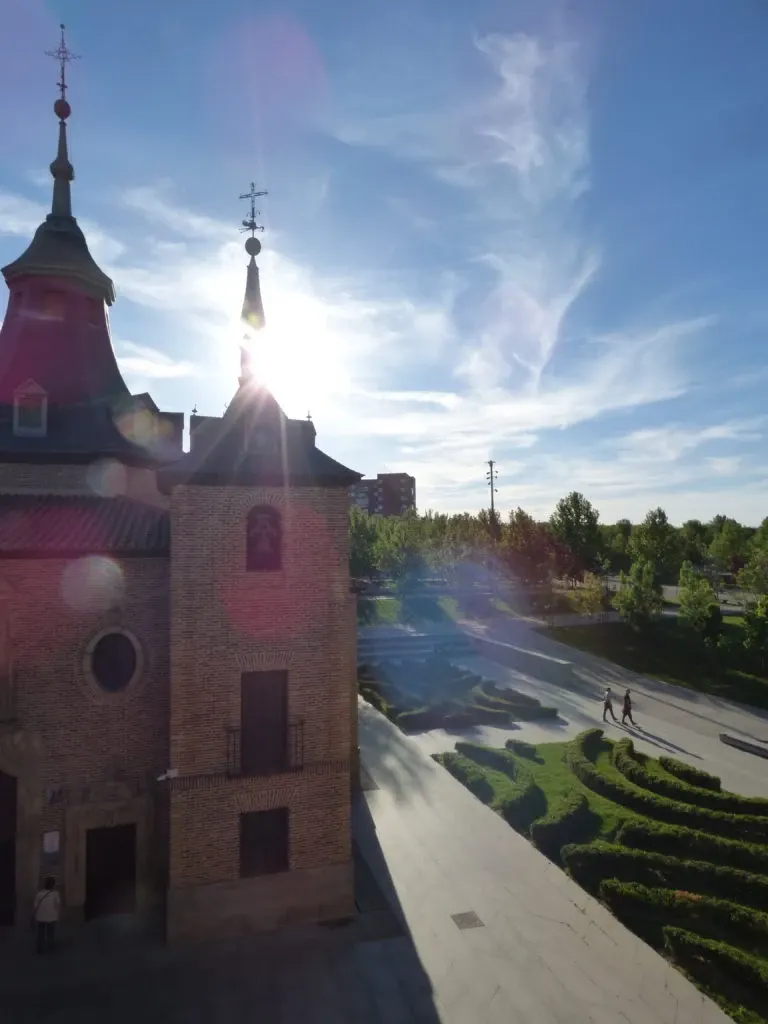Bell tower against the light and dazzling sun above the gardens