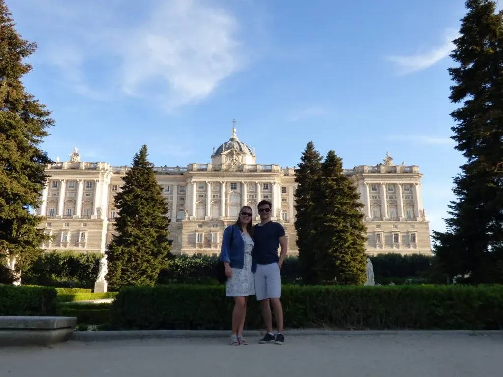 Couple in front of the long pale facade of the Royal Palace