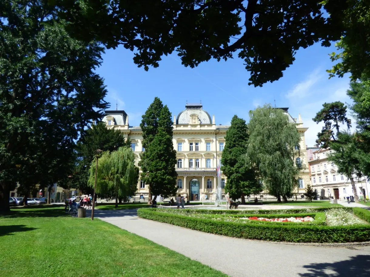 Tree-lined park in front of a large yellow building
